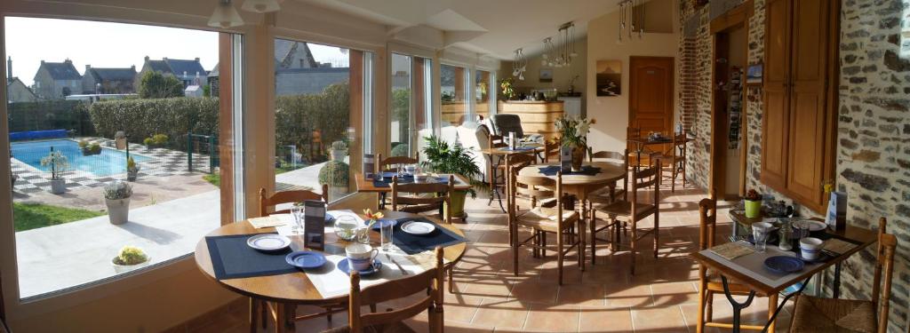 ein Restaurant mit Tischen und Stühlen und einem großen Fenster in der Unterkunft La Grande Mare in Saint-Benoît-des-Ondes