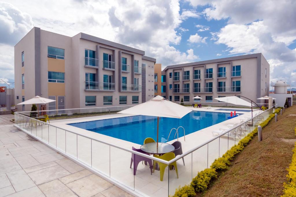 una piscina con mesa y sillas junto a un edificio en Hotel Las Olas Palermo, en Neiva