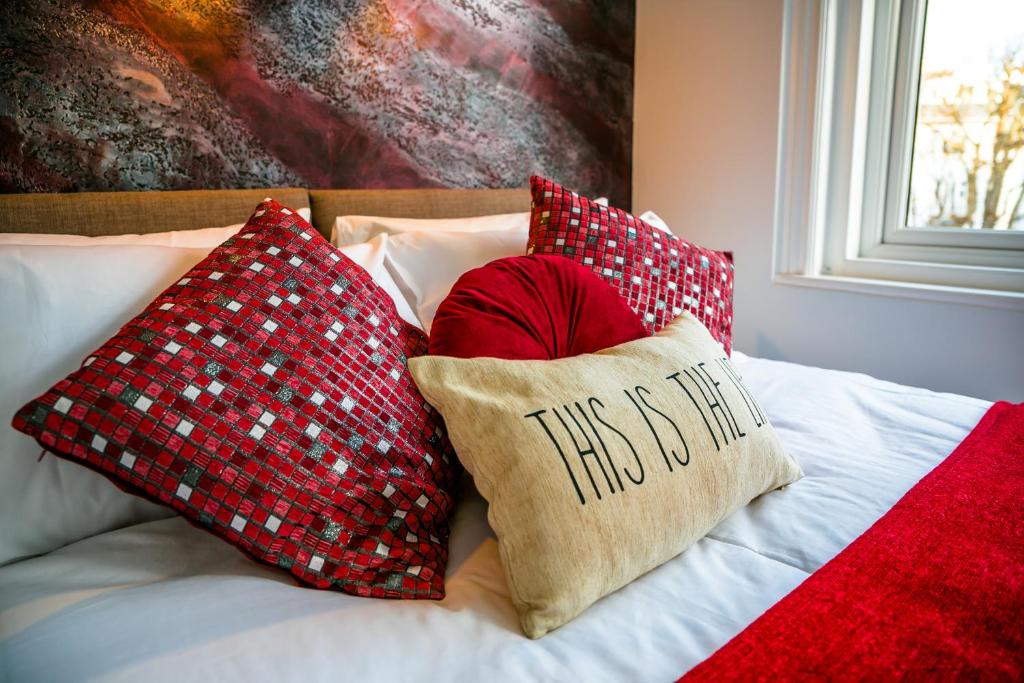 a bed with red pillows and a pillow that says that is me at Meads Apartment in Eastbourne