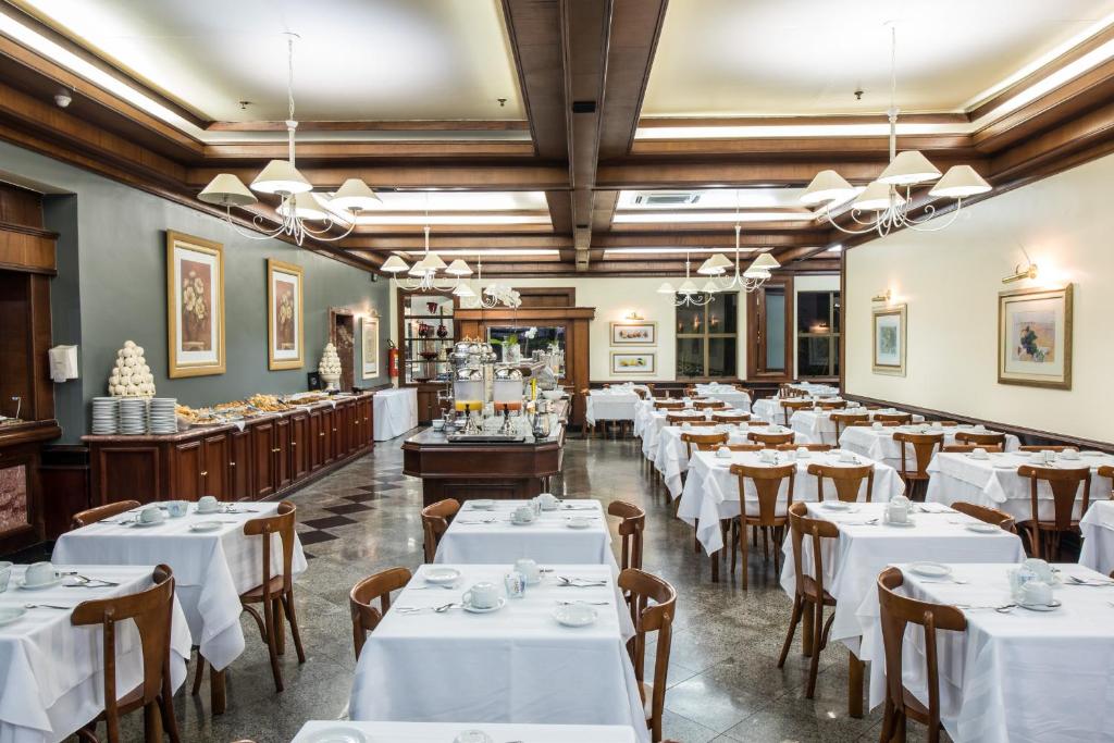 una sala da pranzo con tavoli e sedie bianchi di Hotel Carlton Plaza a Poços de Caldas