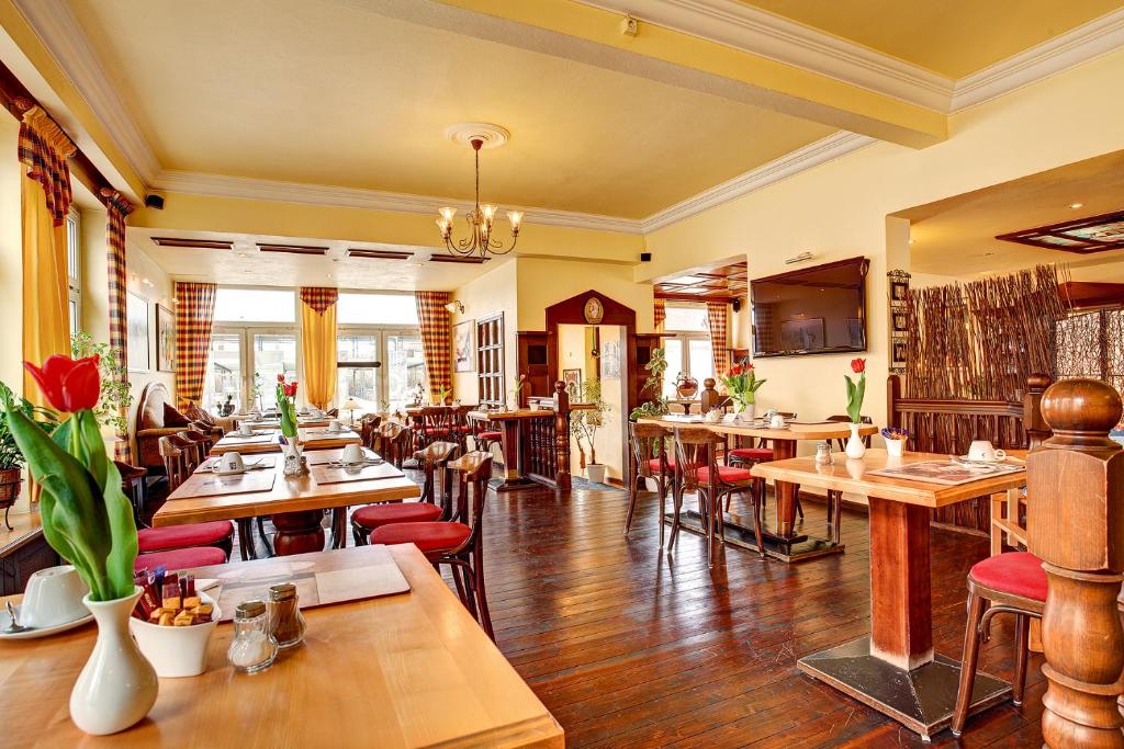 un restaurante con mesas de madera y sillas rojas en Stadthotel Detmold, en Detmold