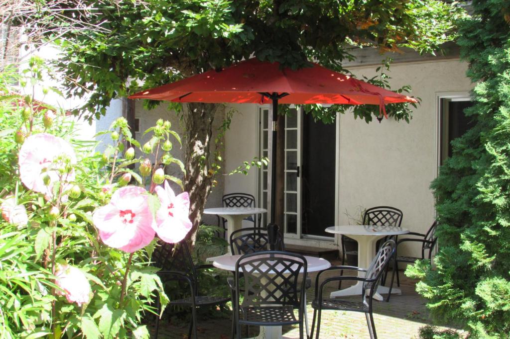 un patio con mesas y sillas bajo una sombrilla roja en Blairpen House Country Inn, en Niagara on the Lake