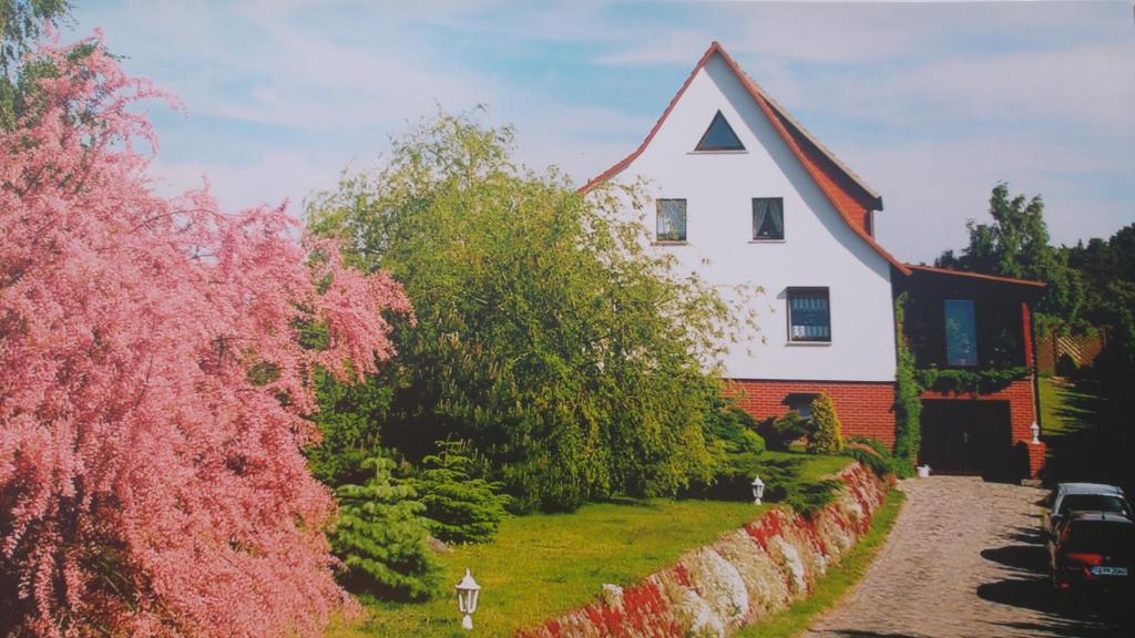 una casa bianca e rossa con recinzione e alberi di Apartments Achterblick a Ueckeritz