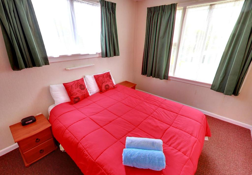 ein Schlafzimmer mit einem roten Bett und einem blauen Kissen darauf in der Unterkunft Belle Bonne Motel in Christchurch