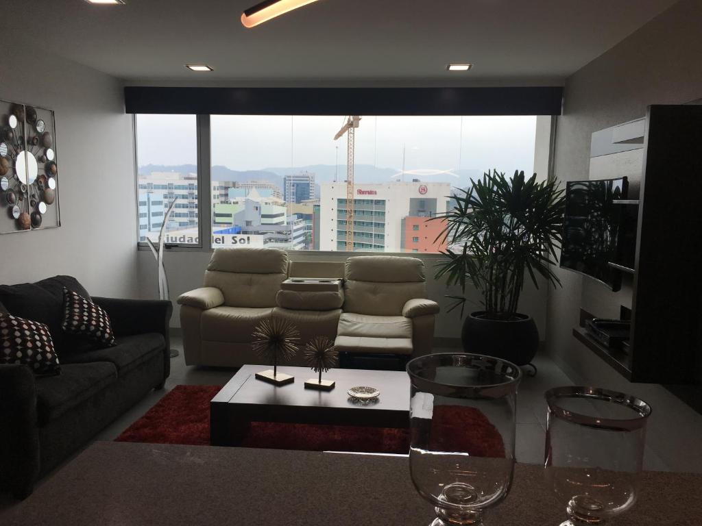 a living room with a couch and a table with wine glasses at LUJO CONFORT SEGURIDAD Quo 101 in Guayaquil