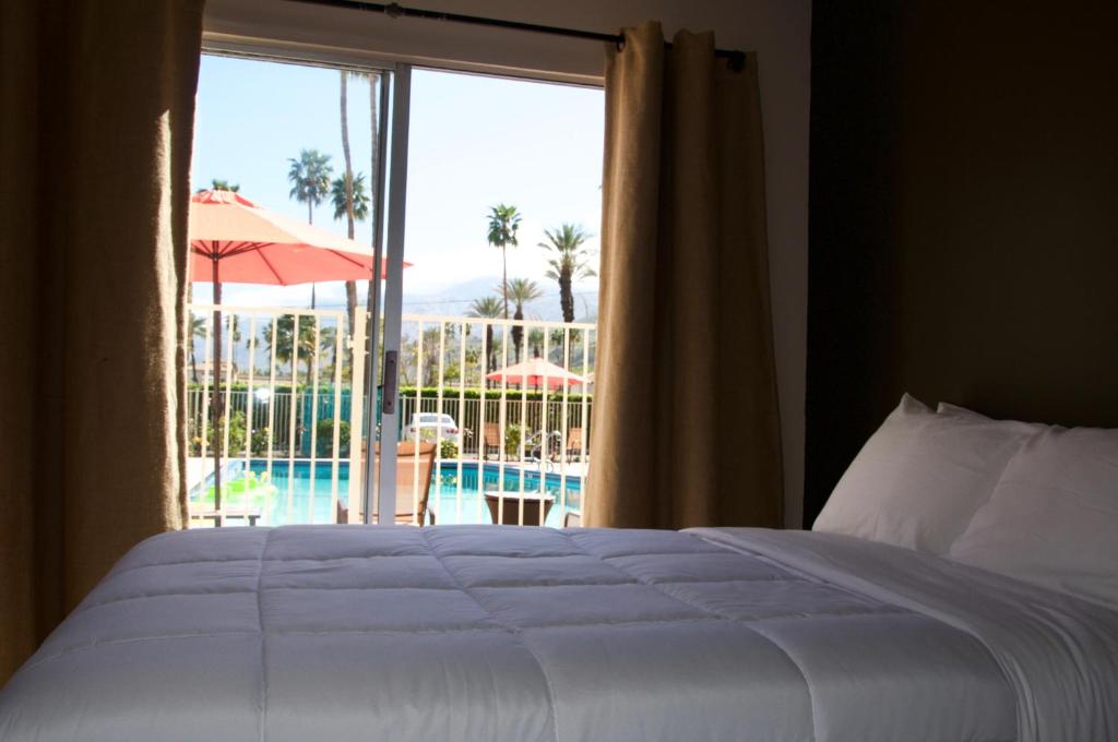 a bedroom with a bed and a view of a pool at Delos Reyes Palm Springs in Palm Springs