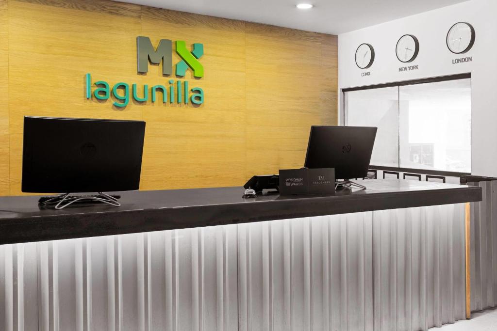 The reception counter has two computer stations beneath the hotel’s branded wall.