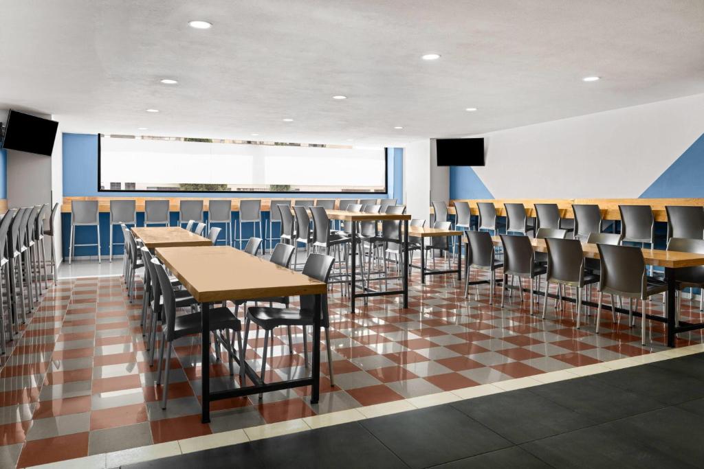 A large breakfast or dining room offers communal tables, individual tables, bar seating, and a checkered floor.