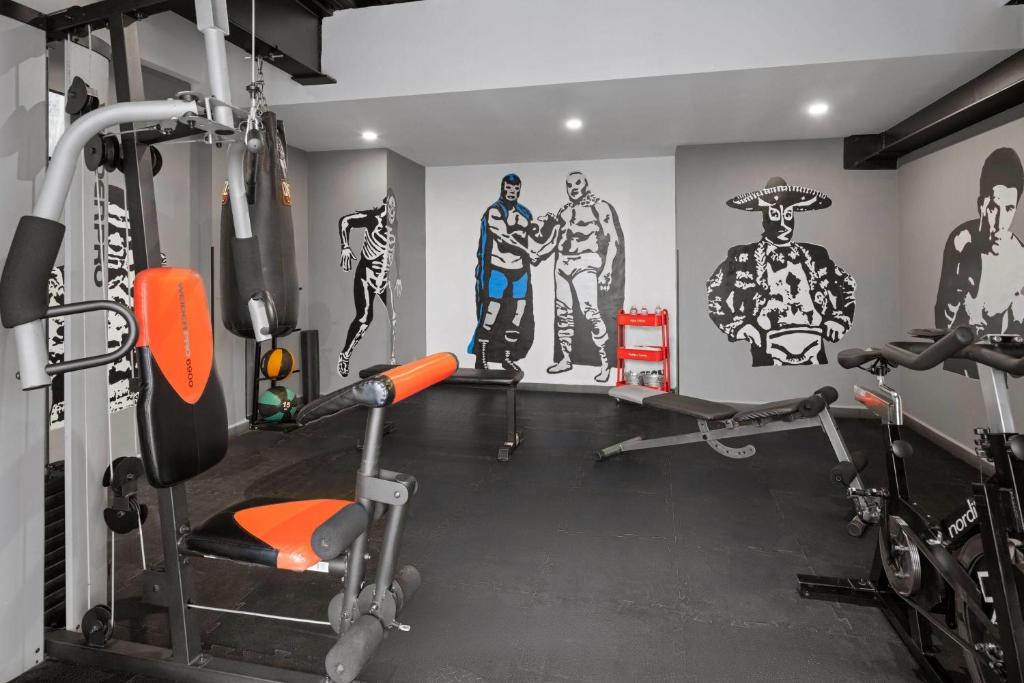 The fitness room combines a cable machine, benches, cardio equipment, and bold athlete murals.