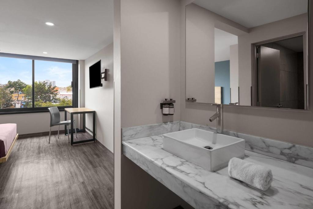 A marble-look vanity sits beside the bedroom, with the shower area visible through the doorway.