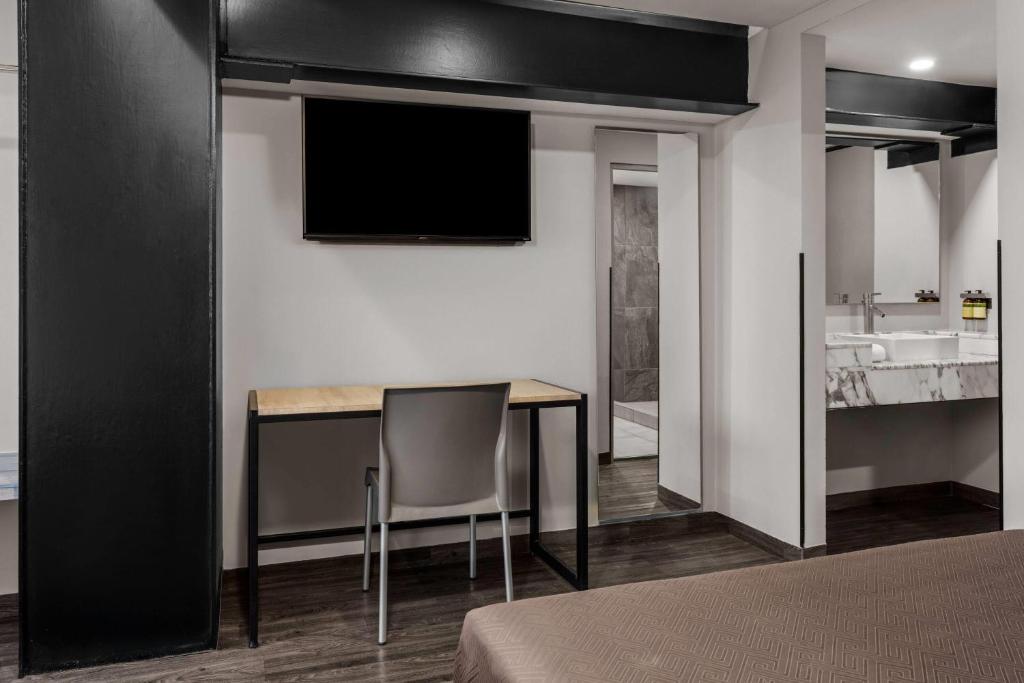 A bedroom corner with a wall-mounted television, desk and open vanity area.