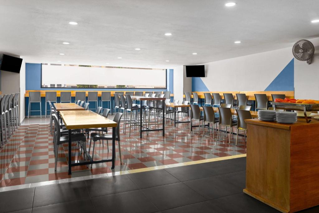A bright breakfast room with communal tables, bar seating and buffet counters.