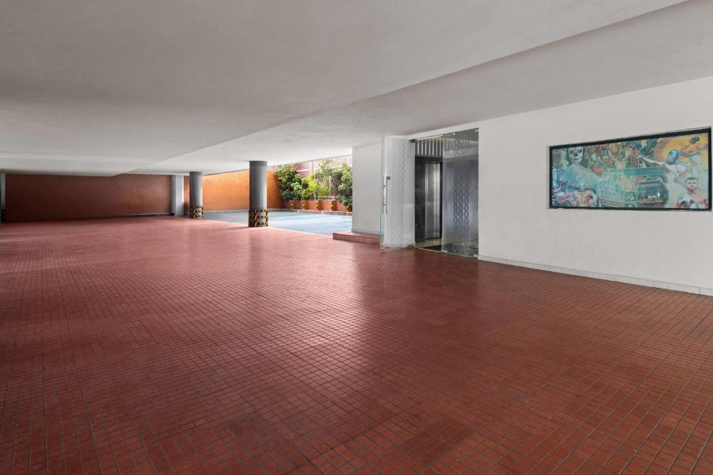 A broad covered hotel entrance area with red tile flooring and artwork.
