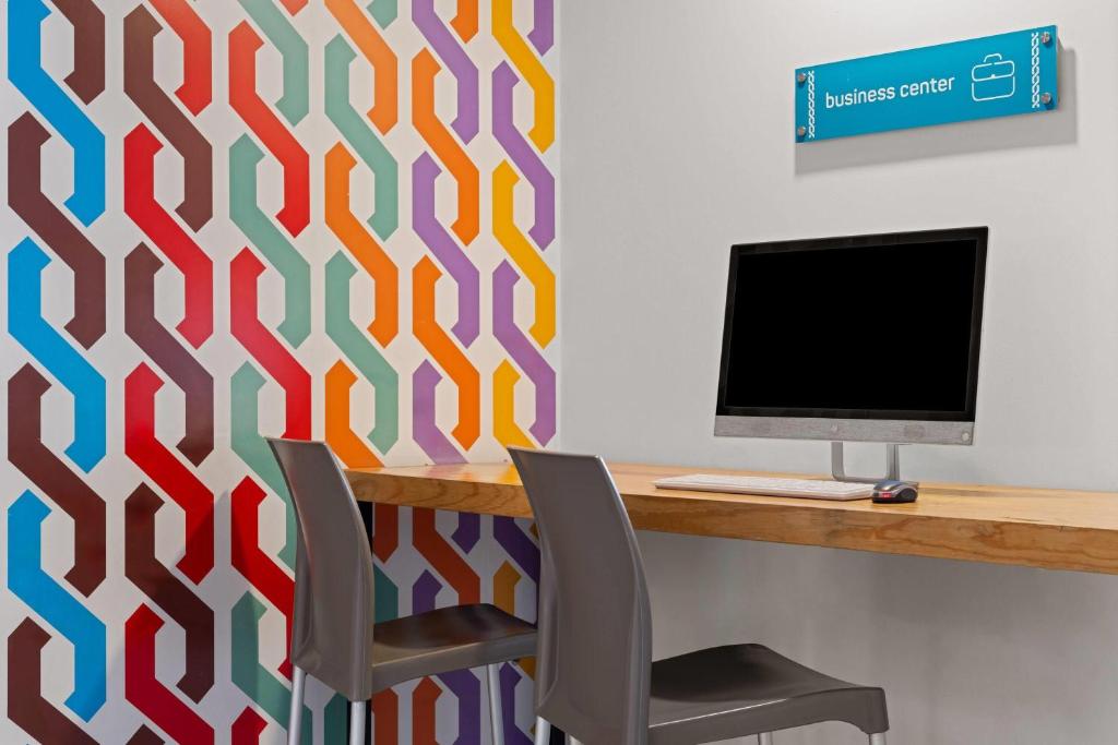 A small business-center workstation with a desktop computer and two chairs.