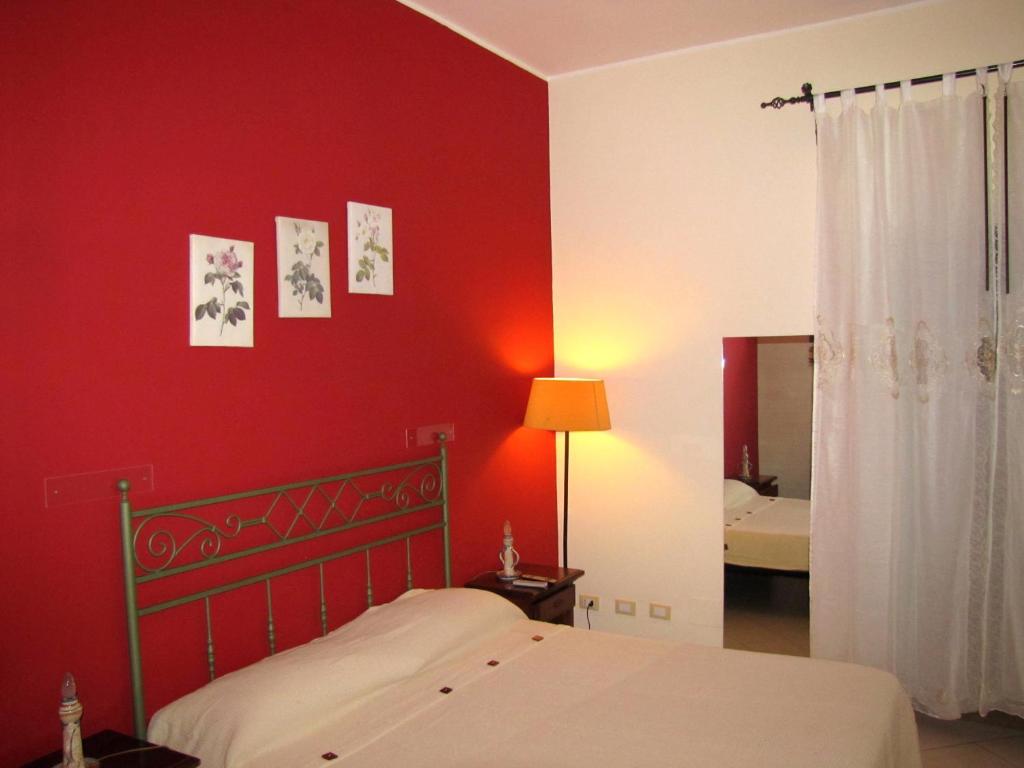 a bedroom with a red wall with a bed and a mirror at Pousada Noir in Trapani