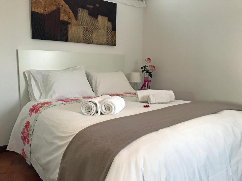 Una cama blanca con dos toallas enrolladas. en Alegria Apartment Porto Downtown, en Oporto