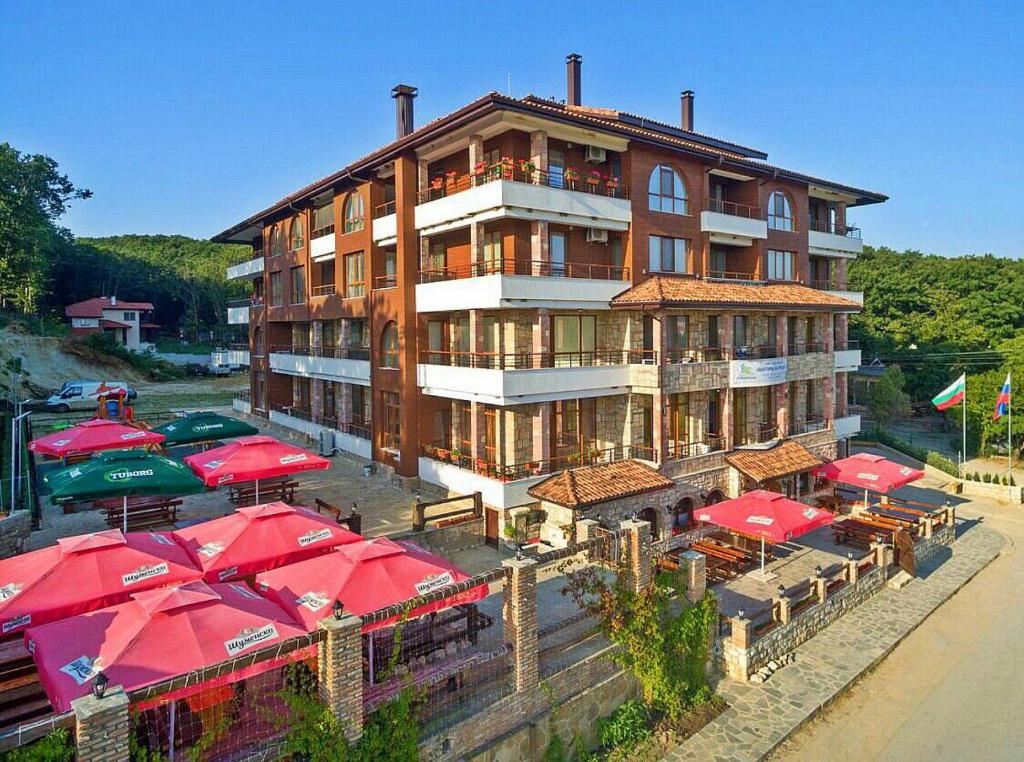 a large building with red umbrellas in front of it at Complex Hunter's Beach in Shkorpilovtsi