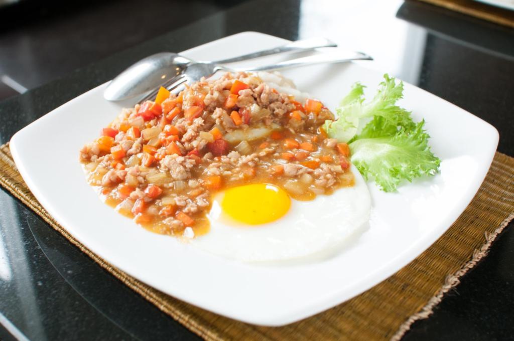 a plate of food with a fried egg and broccoli at Kasemsarn Hotel Chanthaburi in Chanthaburi