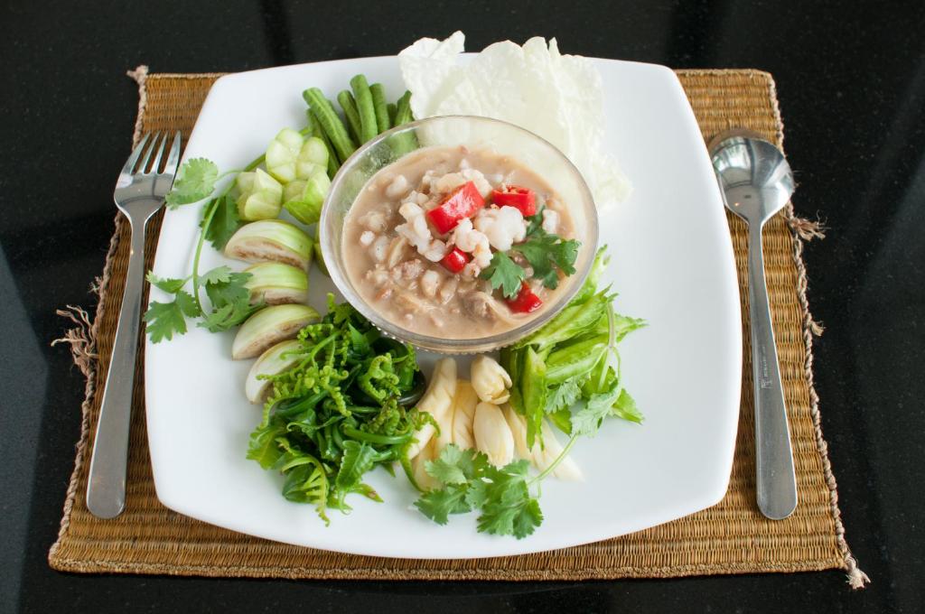 a plate of food with a bowl of soup and vegetables at Kasemsarn Hotel Chanthaburi in Chanthaburi