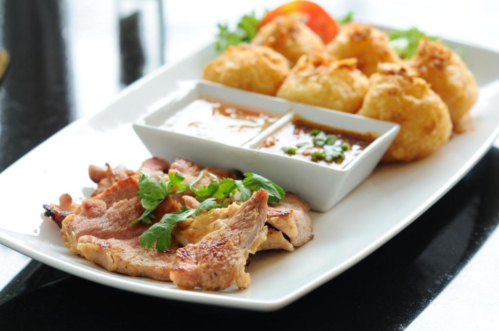 a plate of food with meat and onion rings at Kasemsarn Hotel Chanthaburi in Chanthaburi