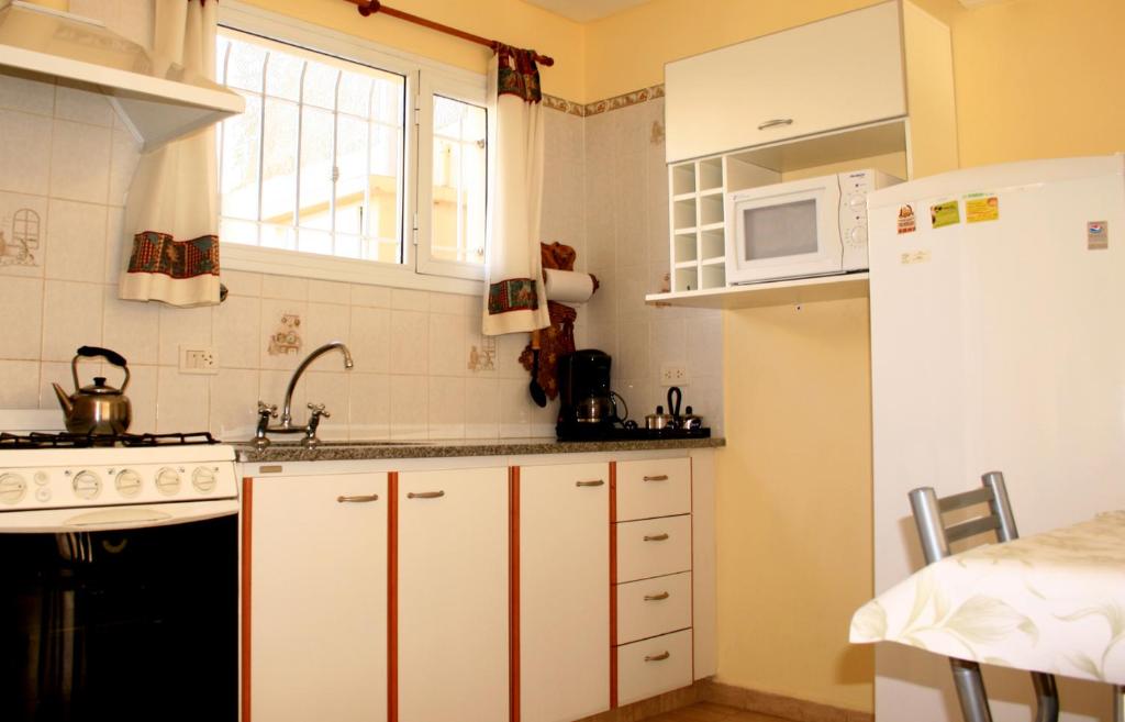 a kitchen with white cabinets and a white refrigerator at Complejo Andalhue in Puerto Madryn