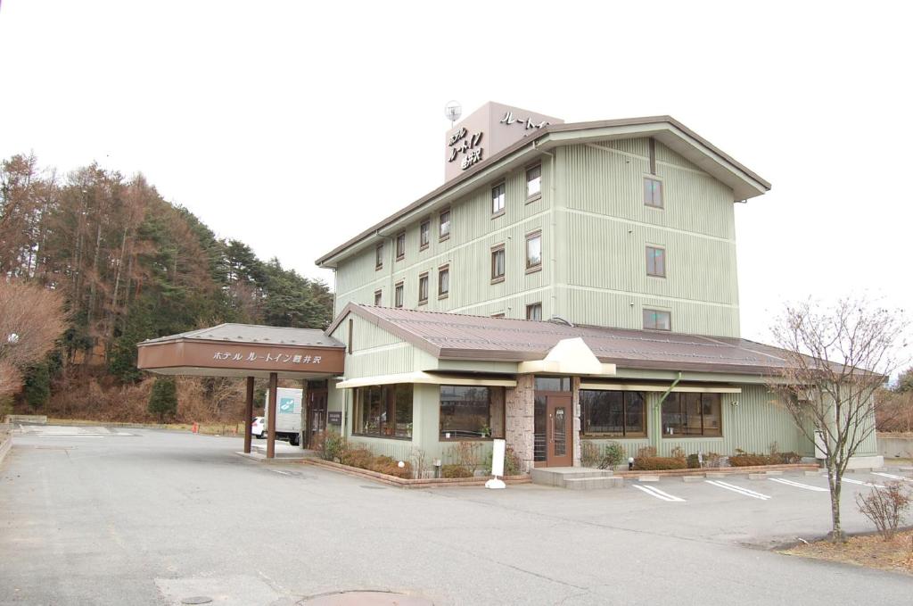 a large building with a parking lot in front of it at Hotel Route-Inn Court Karuizawa in Miyota