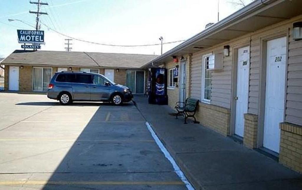 una minivan estacionada en un estacionamiento junto a un motel en California Motel, en California
