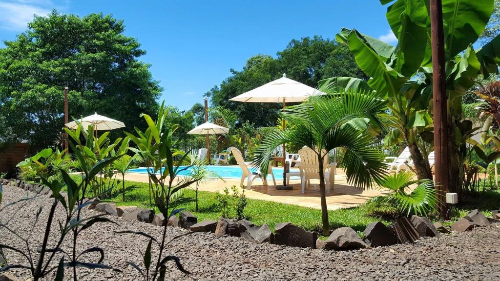 un complejo con piscina, sillas y sombrillas en Terra Lodge en Puerto Iguazú