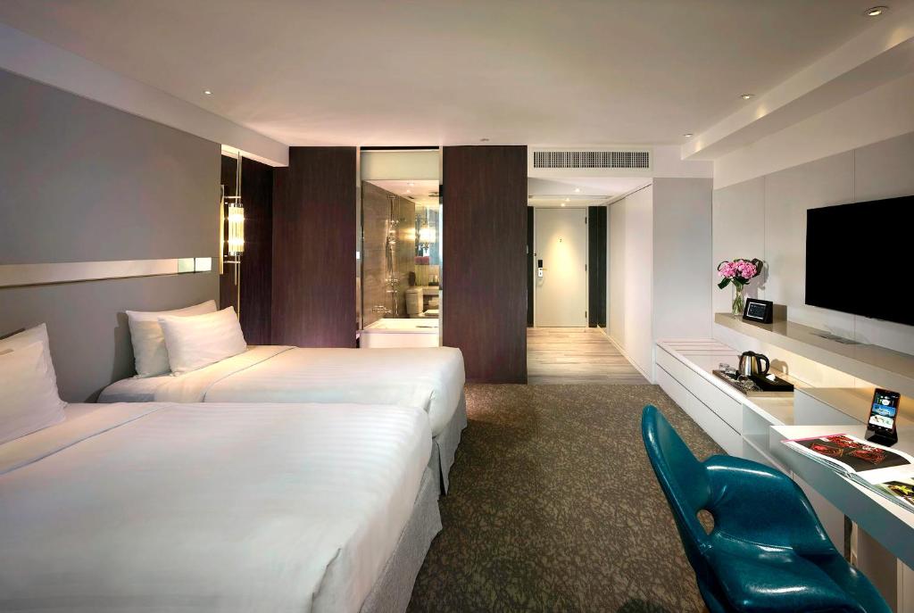 a hotel room with two beds and a television at Nathan Hotel in Hong Kong