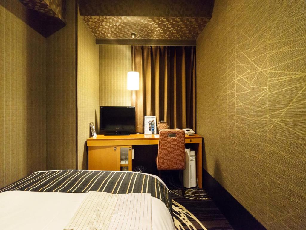 a hotel room with a bed and a desk with a computer at Sotetsu Fresa Inn Higashi Shinjuku in Tokyo