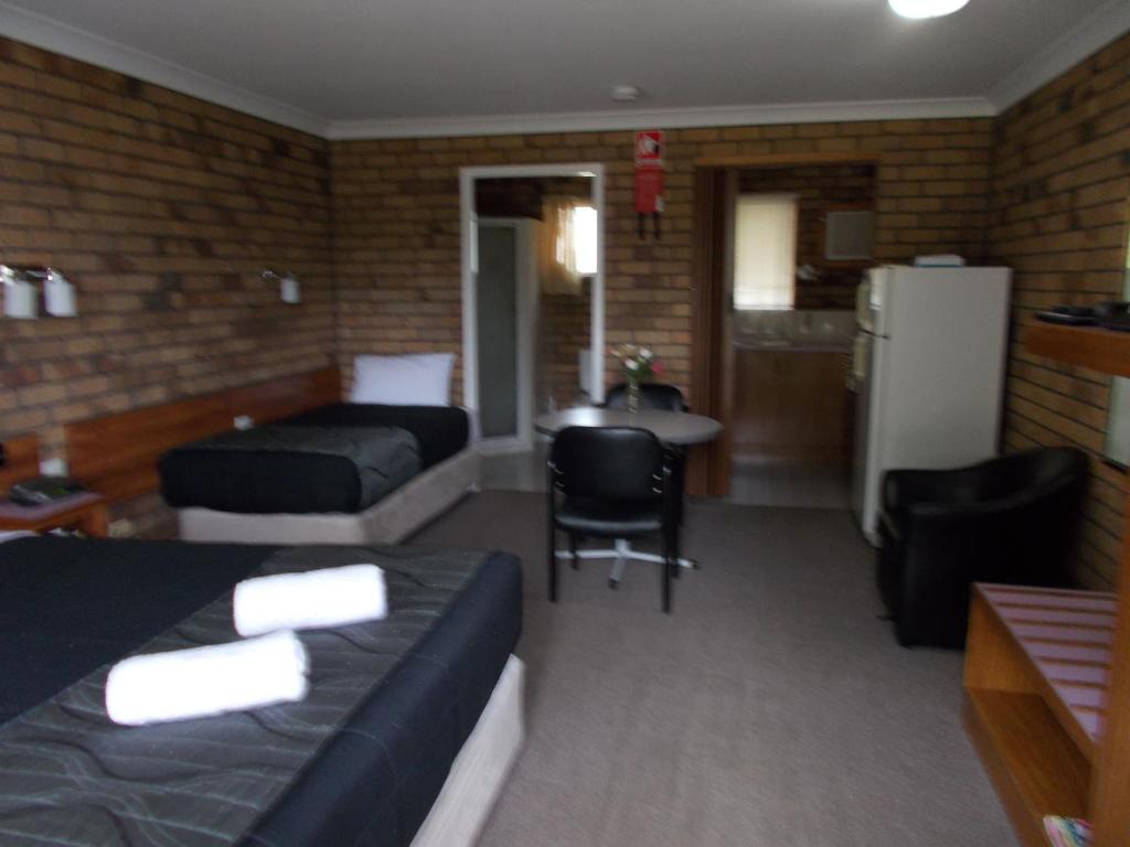a room with a bed and a couch and a table at Park House Motor Inn in Oakey
