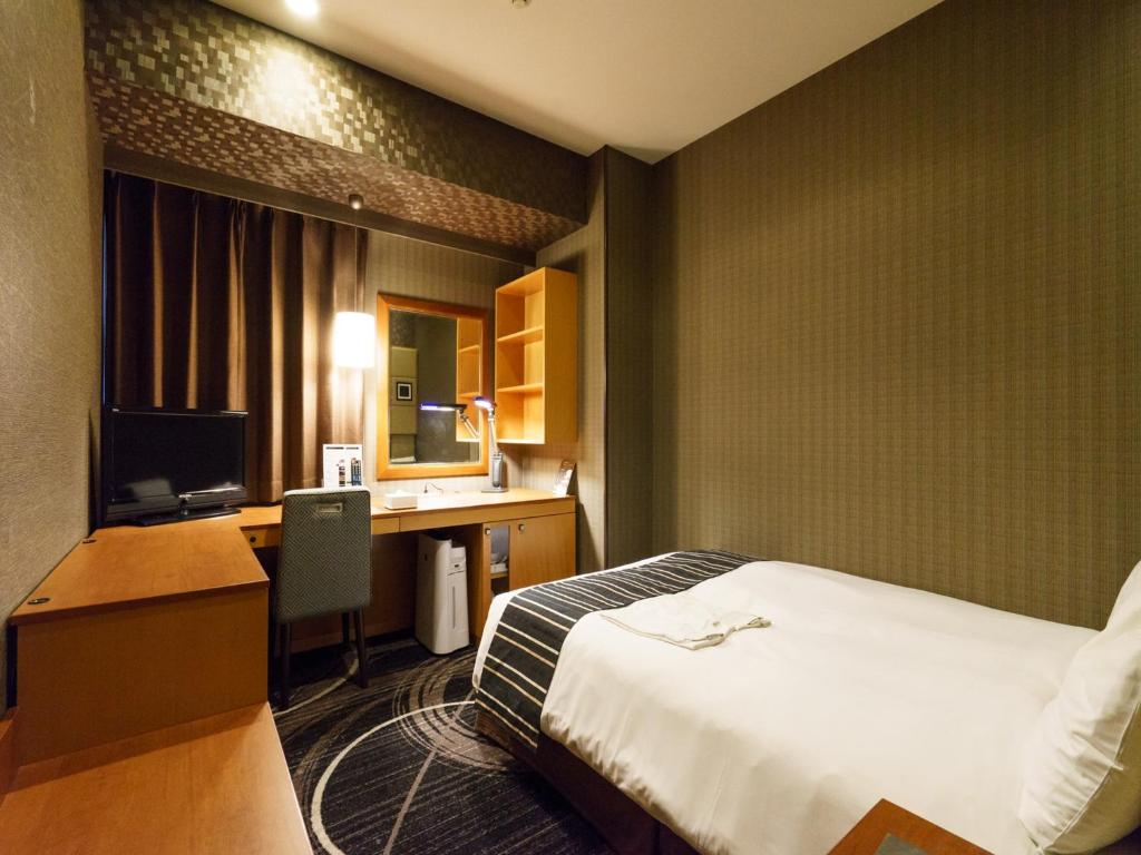 a hotel room with a bed and a desk with a computer at Sotetsu Fresa Inn Higashi Shinjuku in Tokyo
