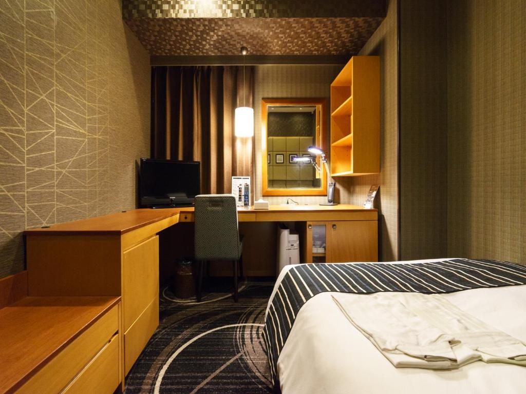a hotel room with a bed and a desk with a computer at Sotetsu Fresa Inn Higashi Shinjuku in Tokyo