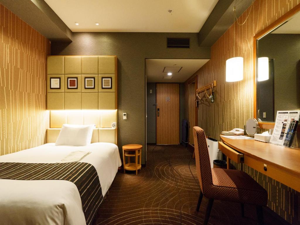 a hotel room with two beds and a desk at Sotetsu Fresa Inn Higashi Shinjuku in Tokyo