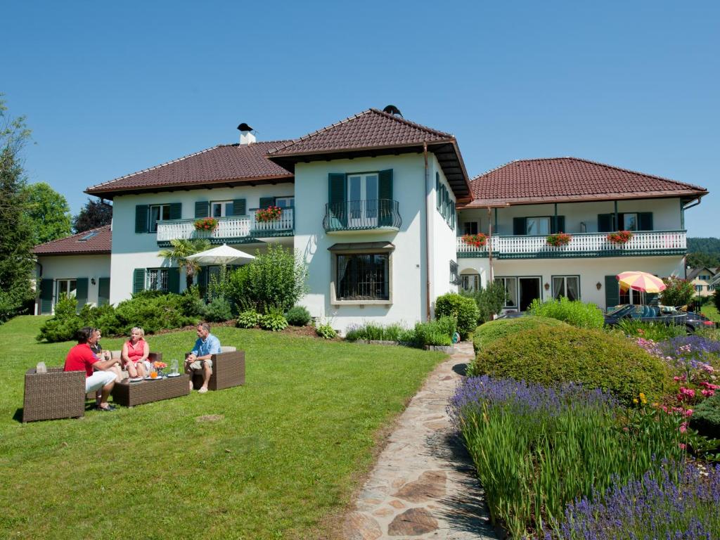 um grupo de pessoas sentadas num relvado em frente a uma casa em Villa Konstanze em Velden am Wörthersee