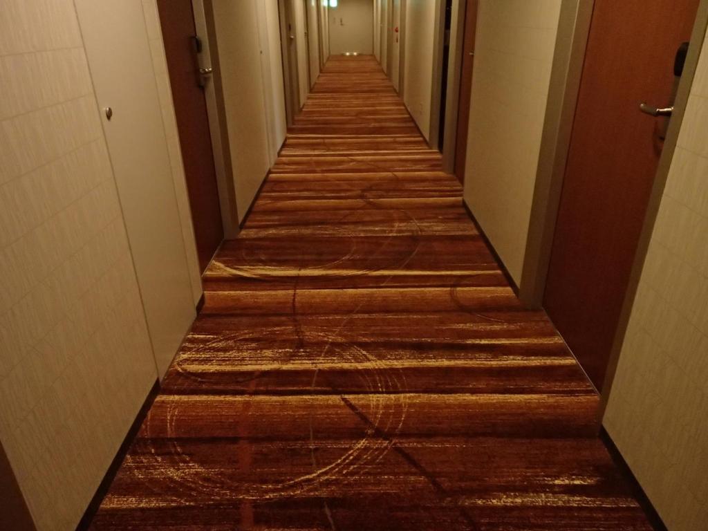 a long hallway with wooden floors in an office building at Sotetsu Fresa Inn Higashi Shinjuku in Tokyo