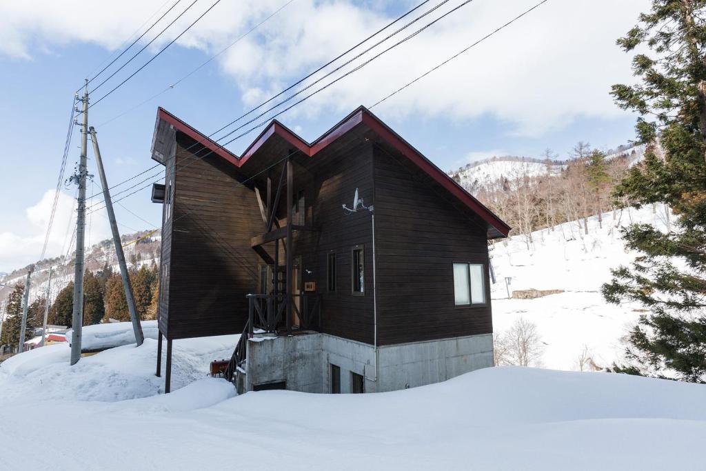 una pequeña casa de madera en la nieve con nieve en Nozawa House, en Nozawa Onsen