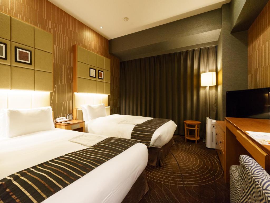 a hotel room with two beds and a television at Sotetsu Fresa Inn Higashi Shinjuku in Tokyo