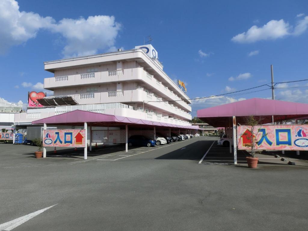 ein großes weißes Gebäude mit Parkplatz in der Unterkunft Hotel Hyper Noah (Adult Only) in Sakai