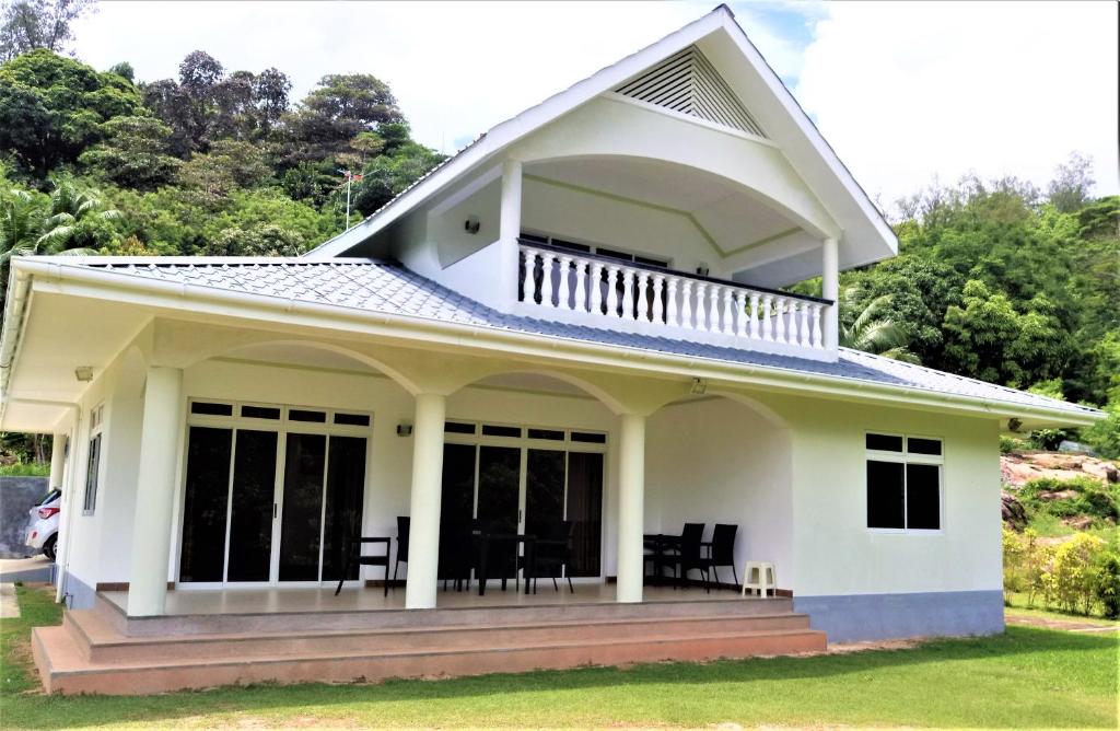 a white house with a balcony on top at Wyn Villa in Anse Possession