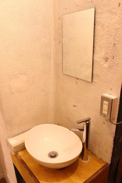 a bathroom with a white sink and a mirror at Guest House MARUYA in Atami