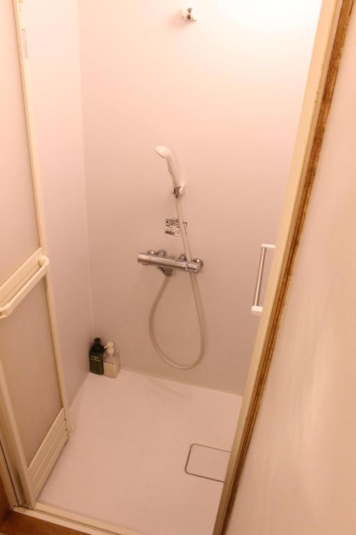 a shower in a white bathroom with a shower at Guest House MARUYA in Atami