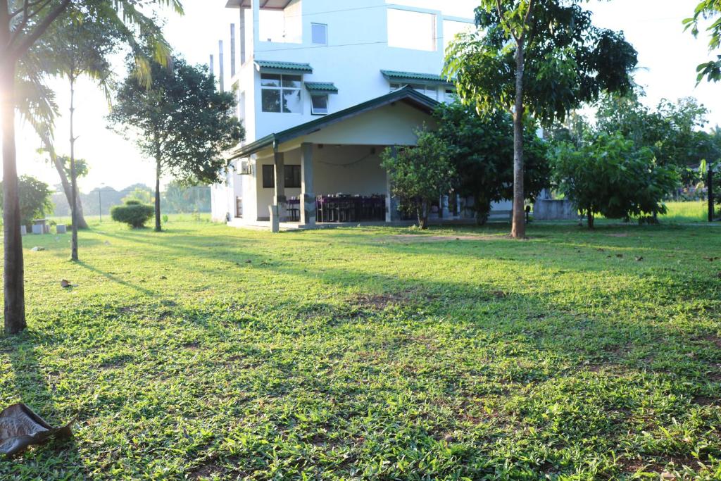 una casa con un patio de césped frente a un edificio en Manel Guest House, en Polonnaruwa