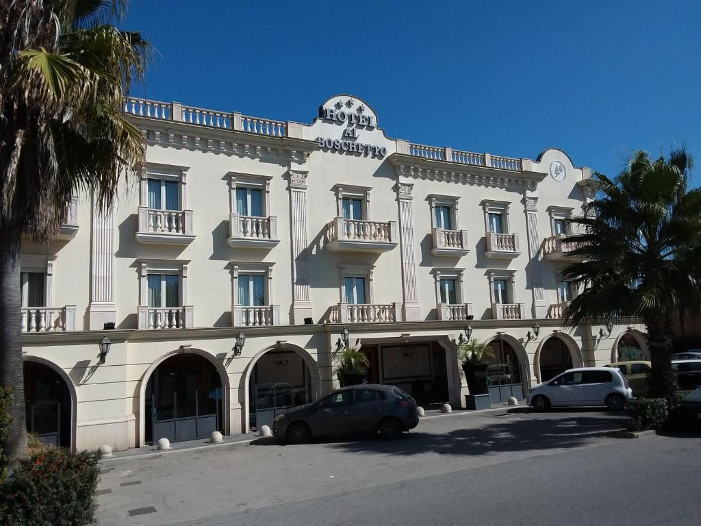 ein großes weißes Gebäude mit davor geparkt in der Unterkunft Al Boschetto in Castel Volturno
