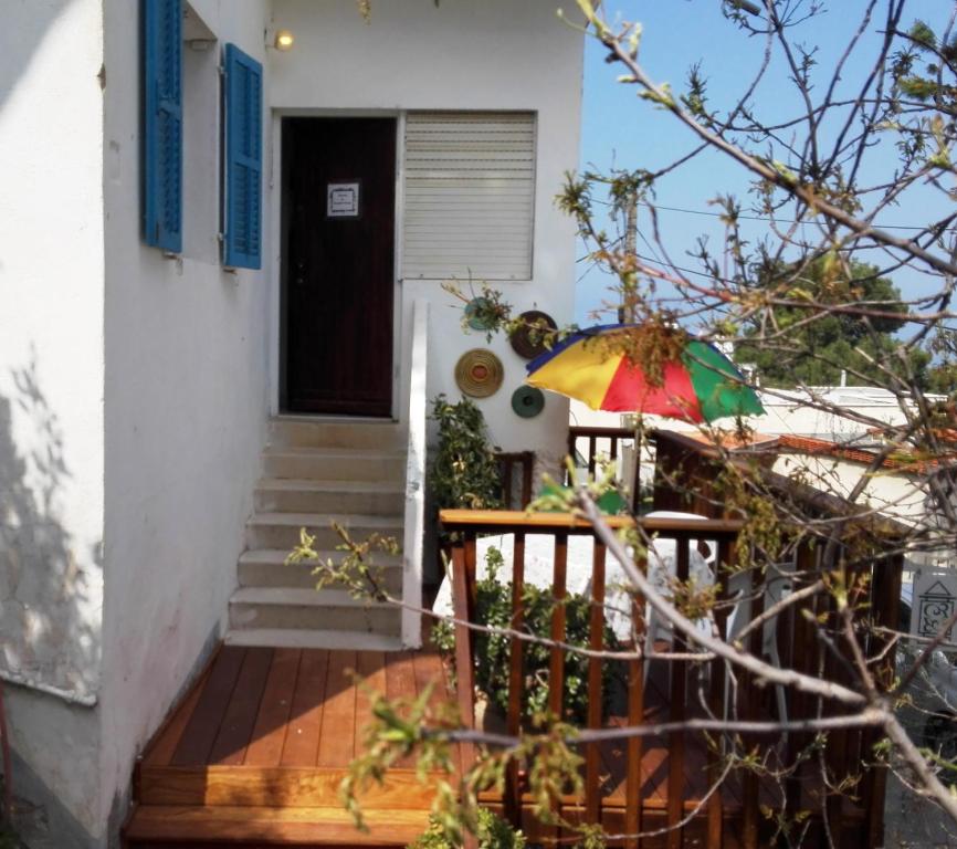 een huis met een houten veranda met een kleurrijke paraplu bij The Artist's House Overlooking the Bay of Haifa in Haifa