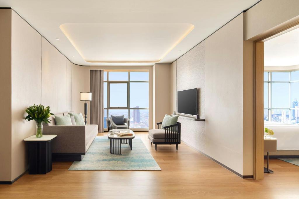 A furnished living room with a sofa, television and city-facing window.