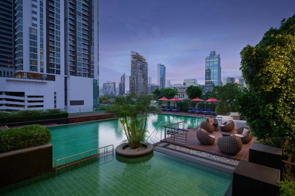 A landscaped outdoor pool terrace overlooking Bangkok’s high-rise skyline.