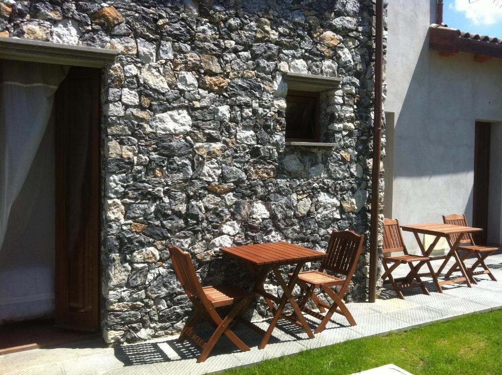 a group of tables and chairs next to a stone wall at Il Casale Del Giglio in Santo Stefano di Magra