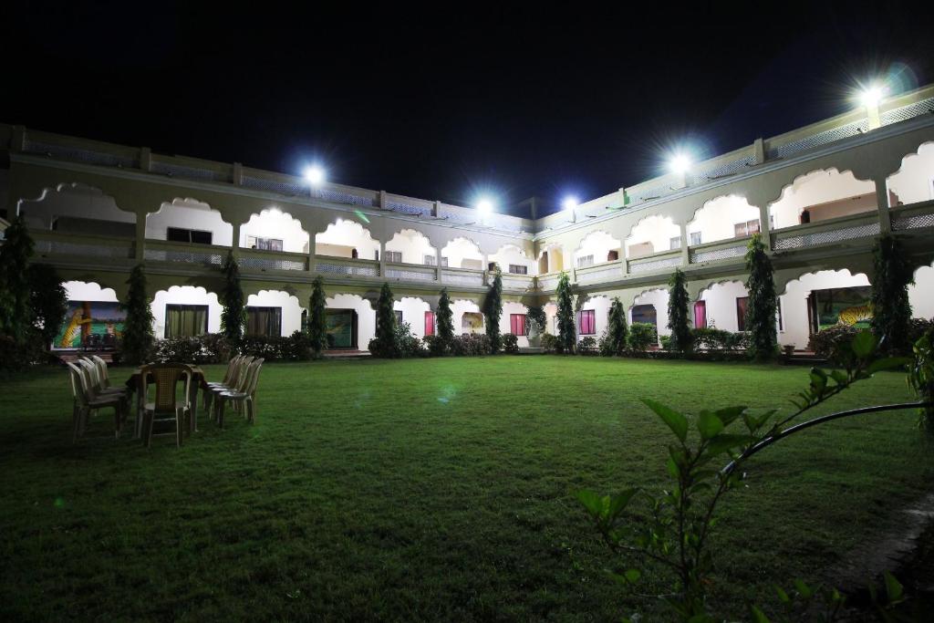 um pátio de um edifício à noite com uma mesa e cadeiras em Goflamingo Resort em Silāri