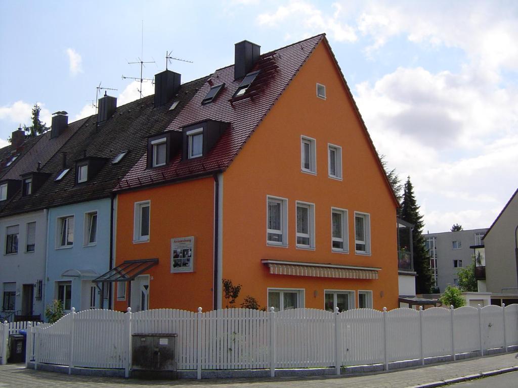 ein großes orangenes Haus hinter einem weißen Zaun in der Unterkunft Ferienhaus Gumann in Nürnberg